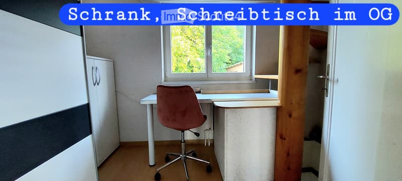A furnished room with a desk, chair, and cabinet, featuring a window with a view of greenery.
