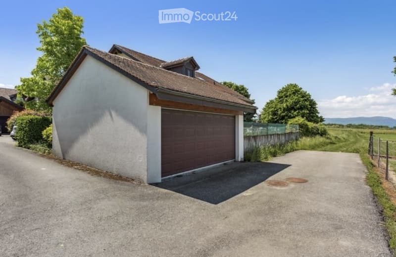Single-story house with a garage, white exterior, brown roof, and a driveway leading to the garage.