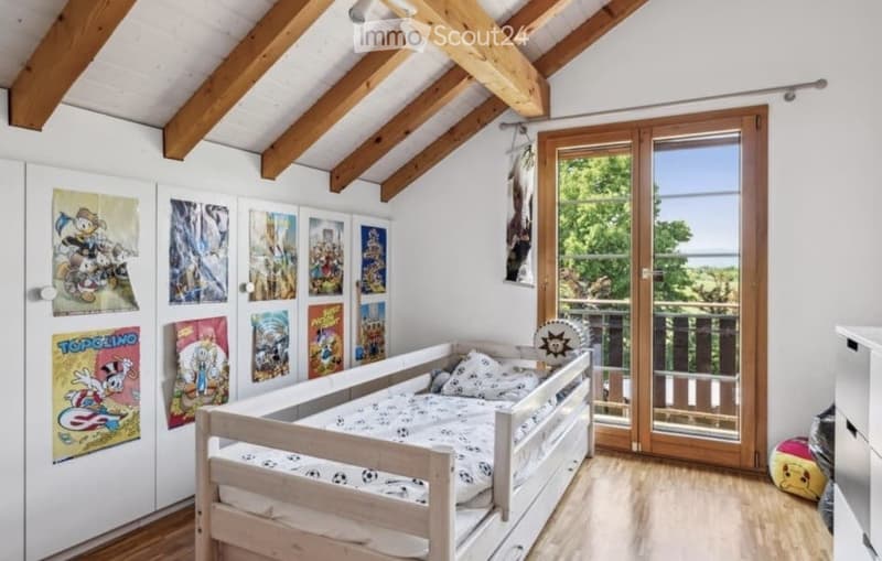 Cozy children's bedroom with wooden bed, colorful posters, and large window with view.