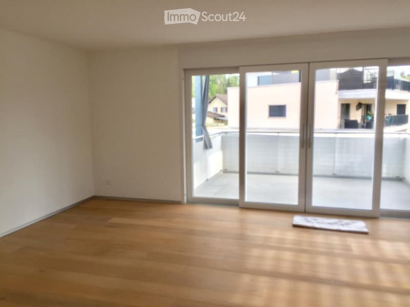Empty room with wooden flooring and large sliding glass doors leading to a balcony.