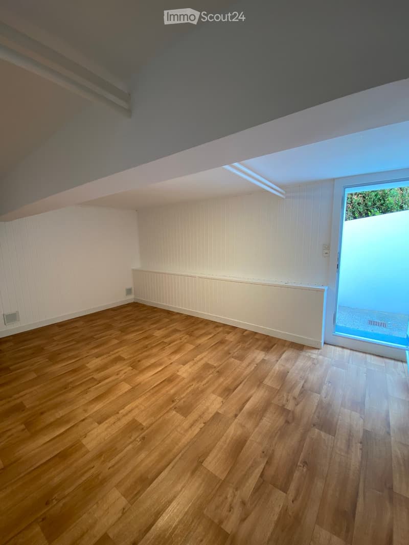 Empty room with wooden flooring, white paneled walls, and a skylight window allowing natural light. No furniture or equipment present.