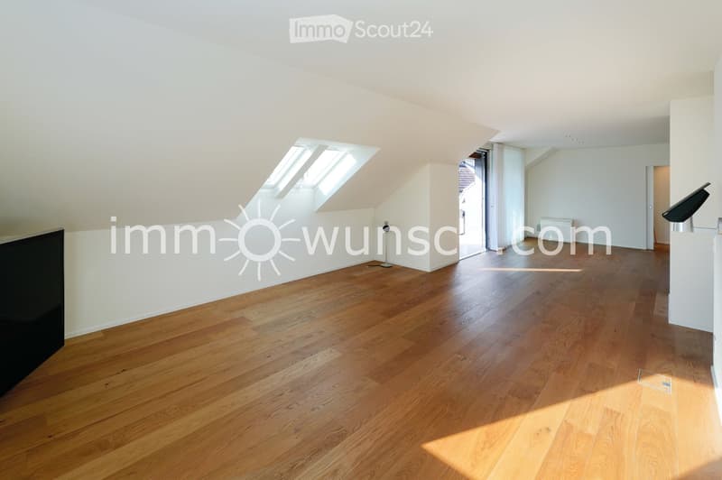 Bright, empty attic room with wooden flooring, white walls, and skylight windows allowing natural light to fill the space.