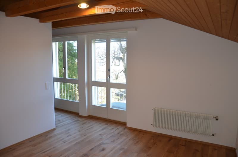 Empty room with wooden flooring, white walls, large windows, and a radiator. No furniture or equipment present.
