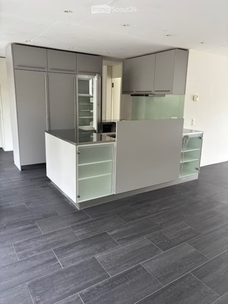 Modern kitchen with grey cabinets, a central island, and a dark grey tiled floor.