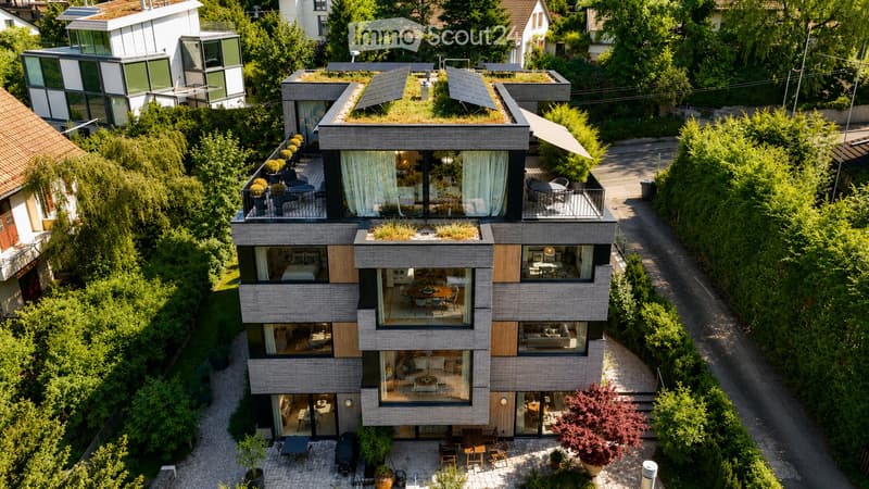 Modern multi-story residential building with large glass windows, balconies, and rooftop greenery. Visible rooms include living spaces, bedrooms, and dining areas.