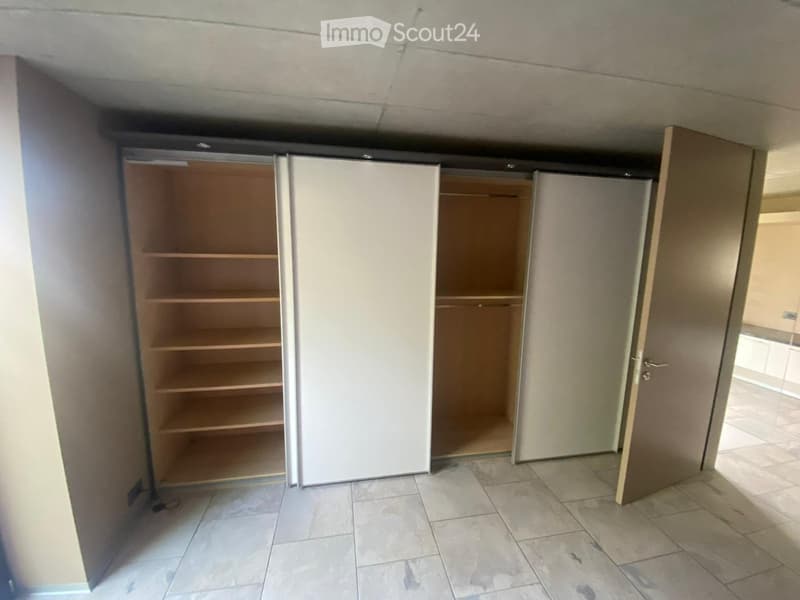 Empty room with tiled floor, white walls, and built-in closet with empty shelves.