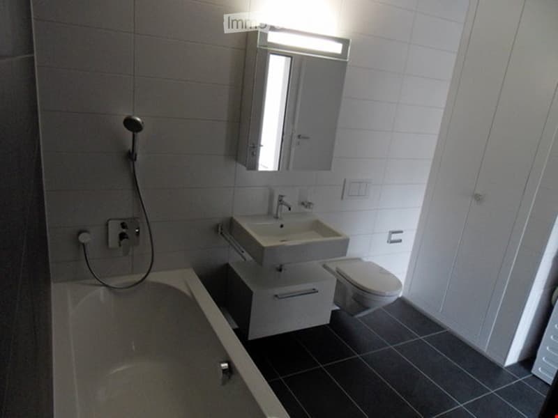 Bathroom with bathtub, sink, toilet, cabinet, shower head