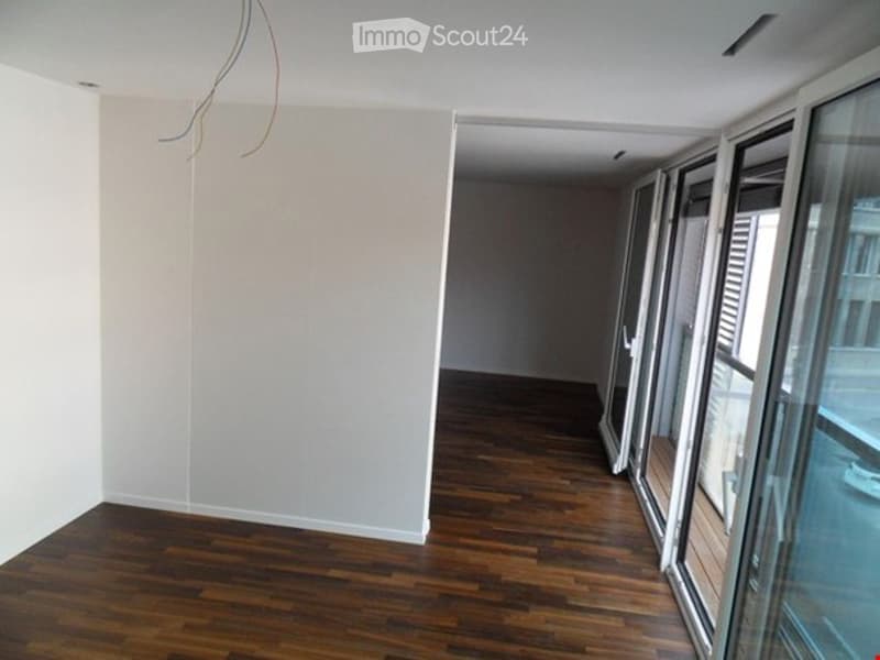 An empty room with hardwood floors and glass doors opening to a balcony.