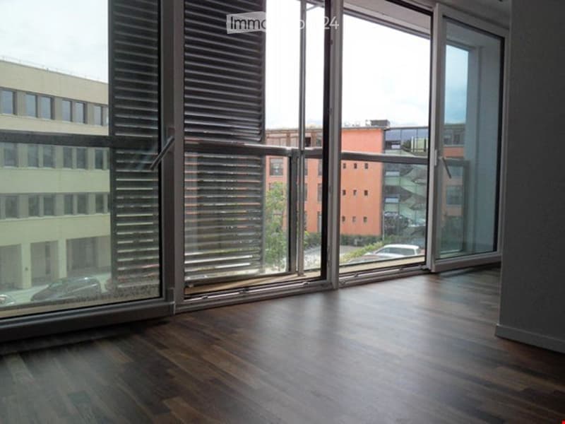 empty room, wooden floor, large glass windows, balcony, view of buildings and trees