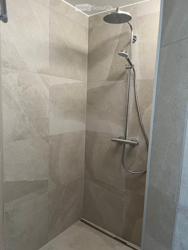 shower area with tiled walls, shower head, and shower hose