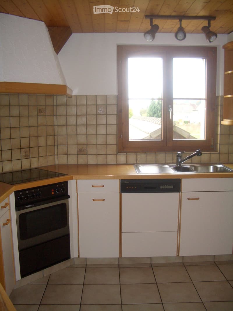 Modern kitchen with white cabinets, wooden countertops, an oven, dishwasher, and a sink with a faucet. The room features tiled walls and a large window offering a view of the outside.