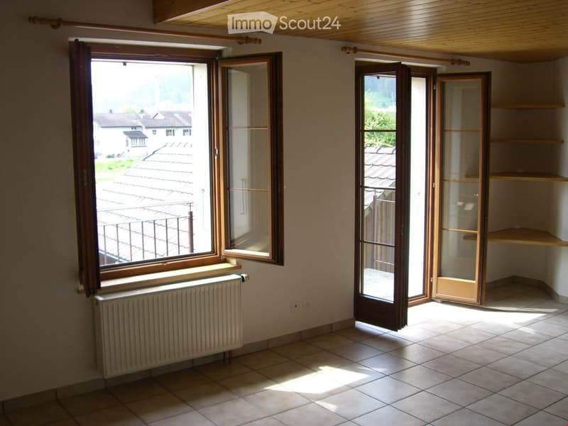 Empty room with tiled floor, wooden-framed windows, radiator, and built-in shelving unit.