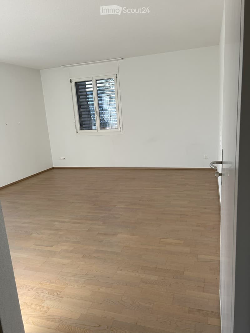 Unfurnished Room. Empty room with light wooden flooring, white walls, and a single window with blinds. No furniture or equipment is present.
