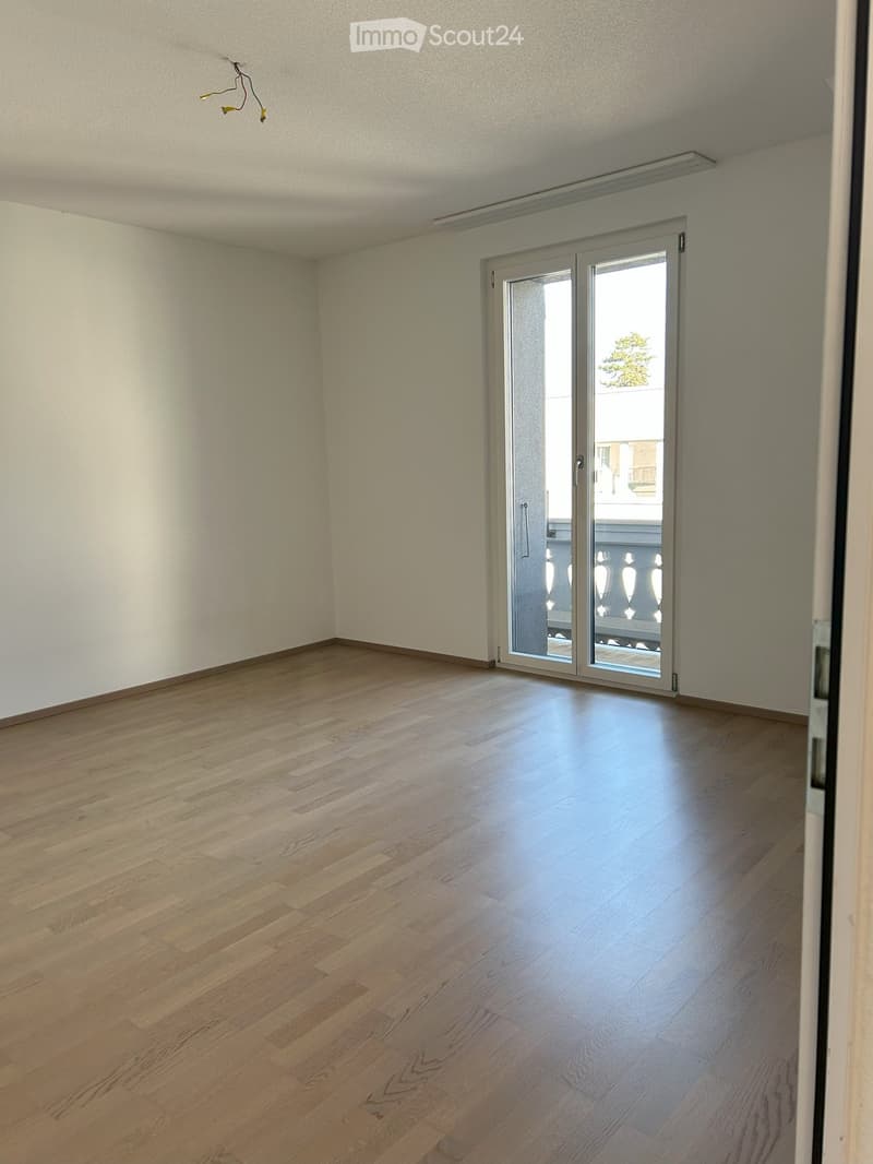 Unfurnished Room. Empty room with light wooden flooring and white walls, featuring a large sliding glass door leading to a balcony.