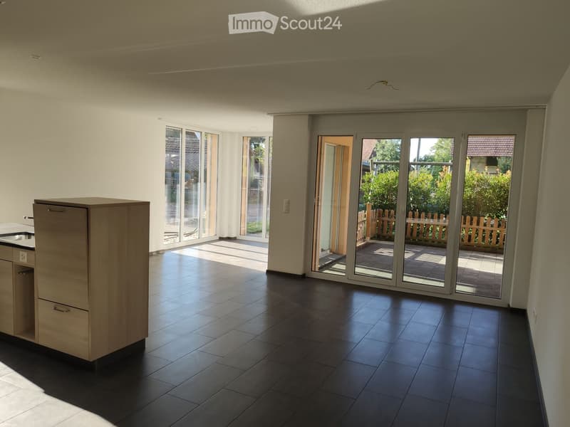 Empty room with dark tiled flooring, light-colored walls, and large sliding glass doors leading to an outdoor area.
