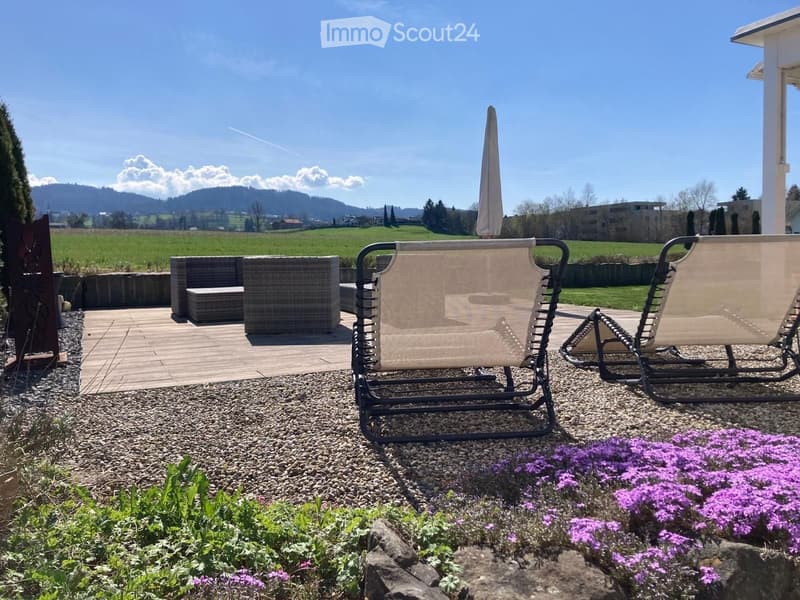 Outdoor patio with lounge chairs, a sofa, and a scenic countryside view.