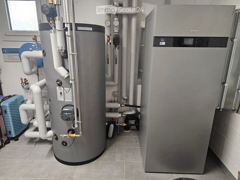 Utility room with a large water heater, boiler, and various pipes and valves.