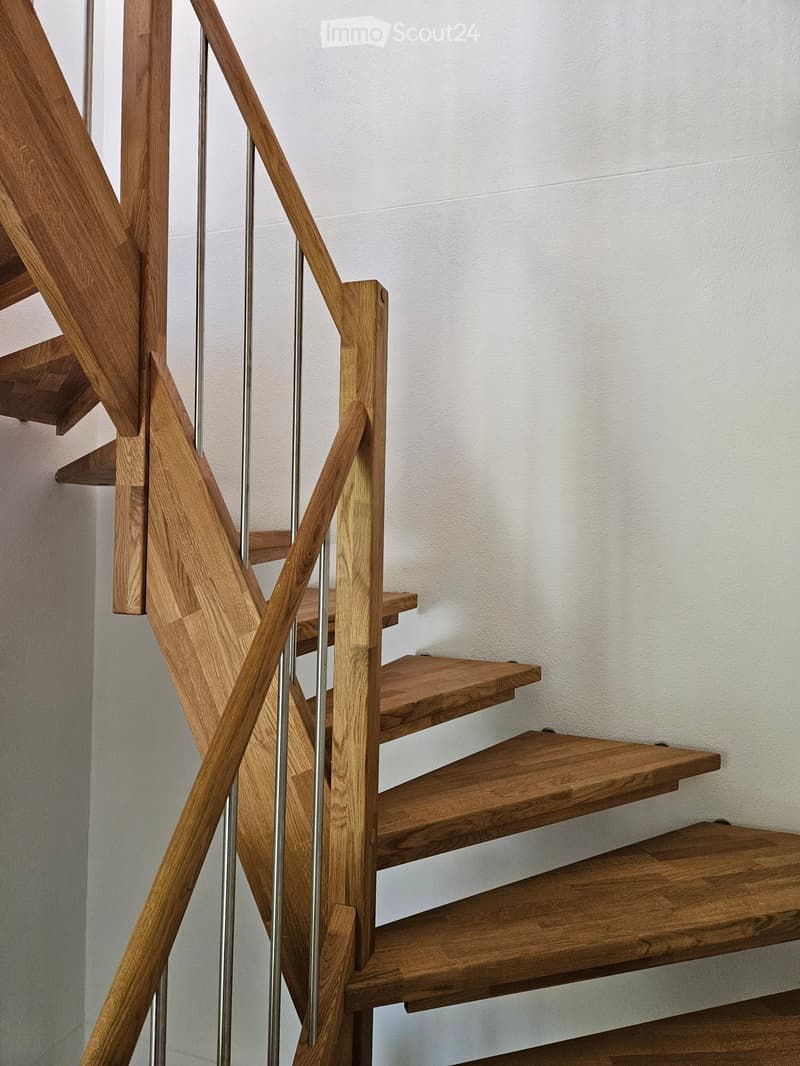 Wooden staircase with metal balustrade, light-colored walls, and wooden flooring.