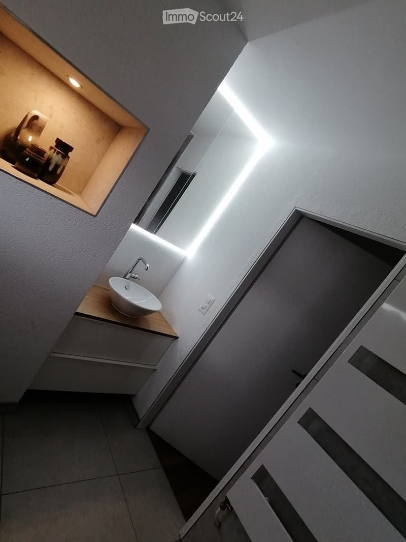 Bathroom with sink, wooden countertop, white tiles, mirror, power outlet, wooden shelf with decorative items