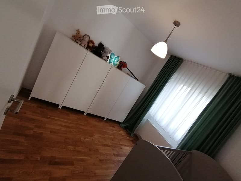 white cabinets, wooden floor, white walls, green curtains, white window, lamp, toys on top of the cabinet