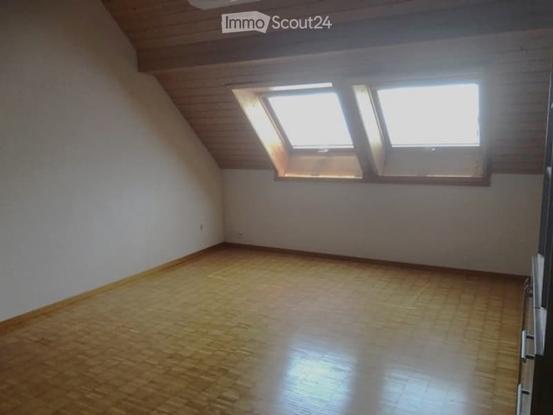 Empty attic room with wooden flooring and skylight windows, no furniture or equipment.