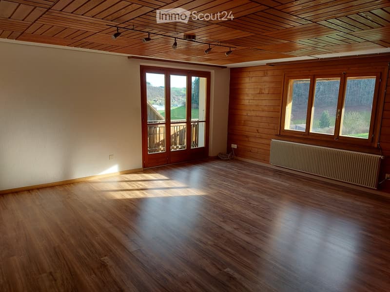 Empty room with wooden flooring, wooden ceiling, large windows, and a radiator. No furniture or equipment present.