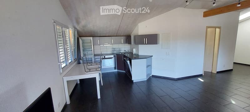 Modern kitchen with dark tiled flooring, white walls, and grey cabinets. Features a white dining table with chairs, a refrigerator, oven, and dishwasher.