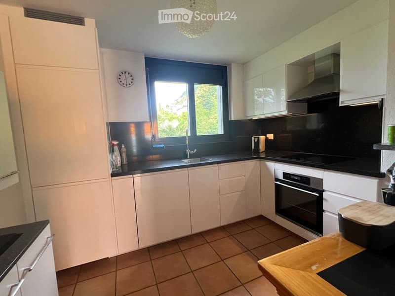 Modern kitchen with white cabinets, black countertops, and stainless steel appliances, including a refrigerator, oven, and sink.