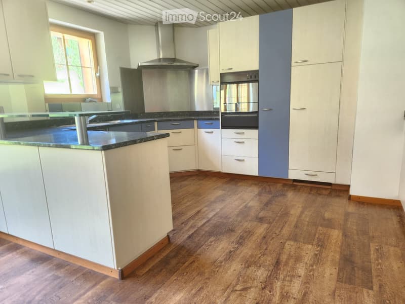 Modern kitchen with white cabinets, dark granite countertops, stainless steel appliances, and wooden flooring.