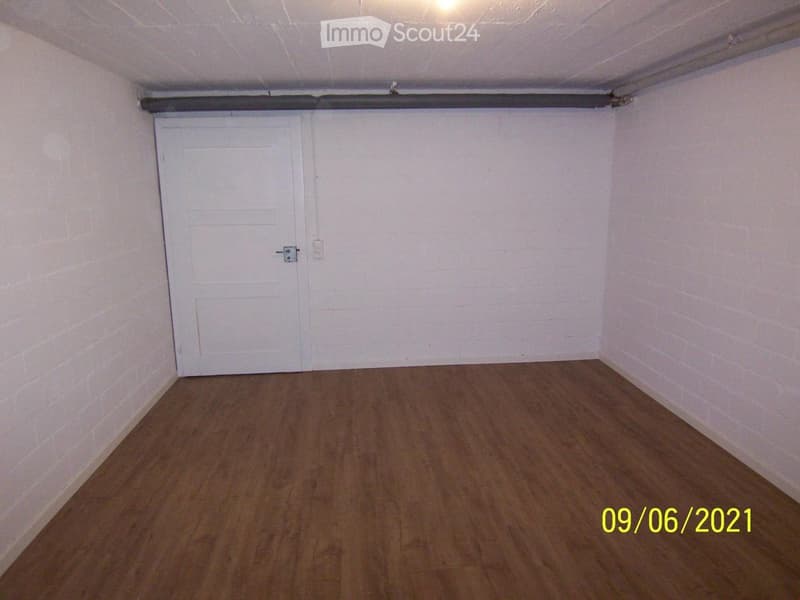 Empty room with wooden flooring, white walls, and a single white door.
