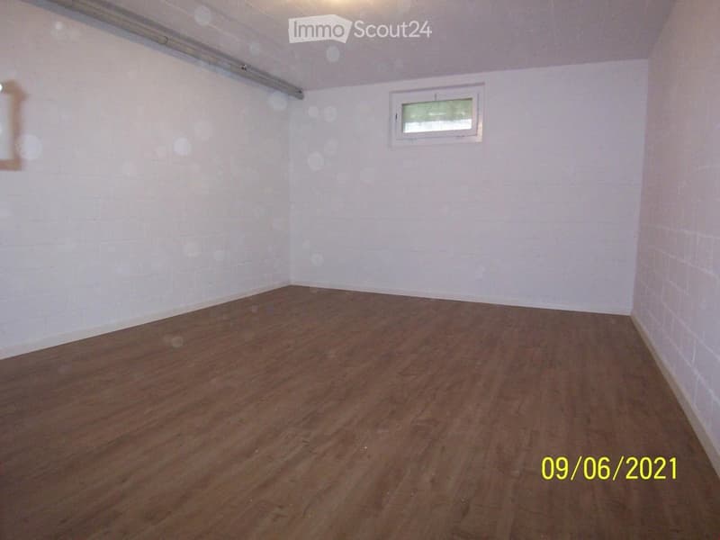 Empty room with white walls, wooden flooring, and a small window. No furniture or equipment present.