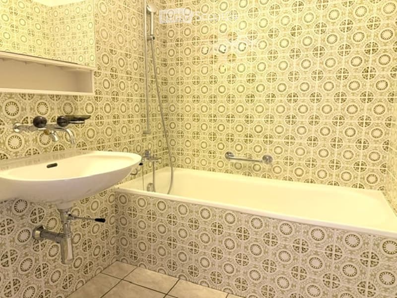Bathroom with a white sink, bathtub, and patterned tiles on walls and floor.
