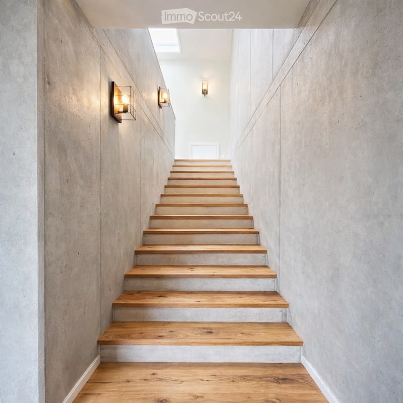 Modern staircase with wooden steps and concrete walls, illuminated by wall-mounted lights and a skylight at the top.