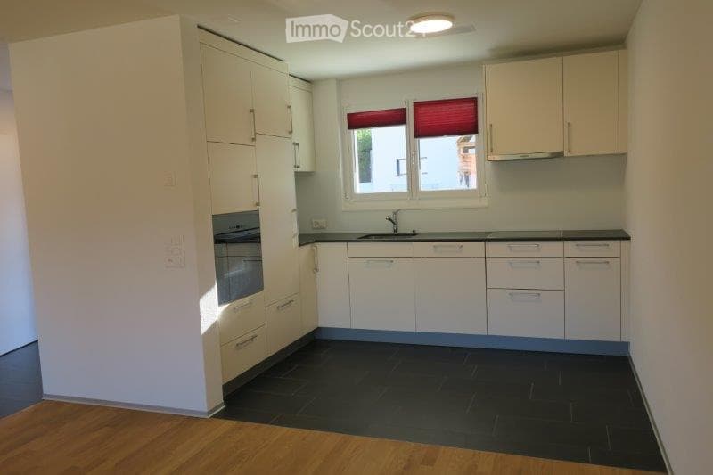 Modern kitchen with white cabinets, black countertops, and a dark tiled floor. Features a sink with a faucet and an oven built into the cabinetry.