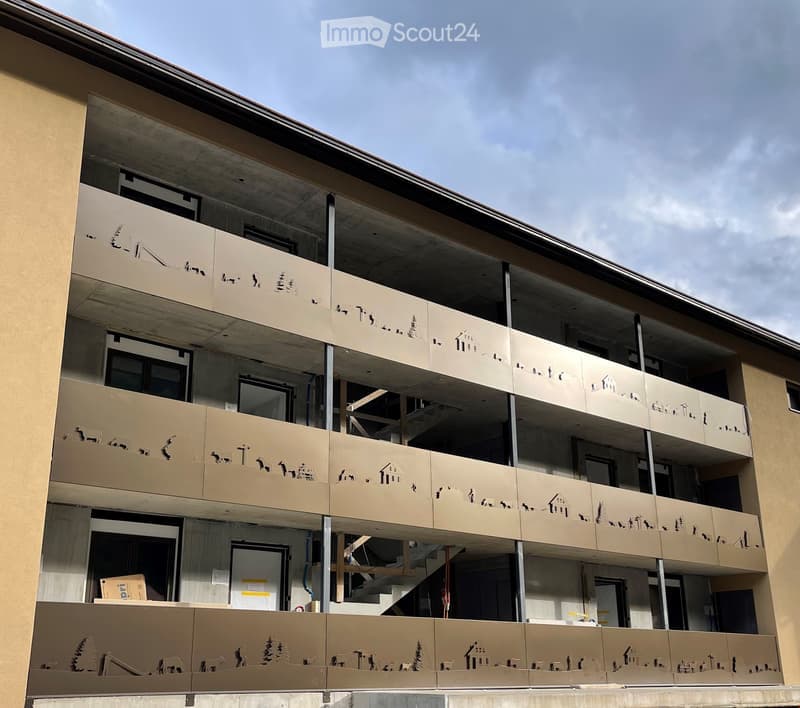 Multi-story residential building with beige facade, multiple windows, and balconies featuring decorative metal railings.