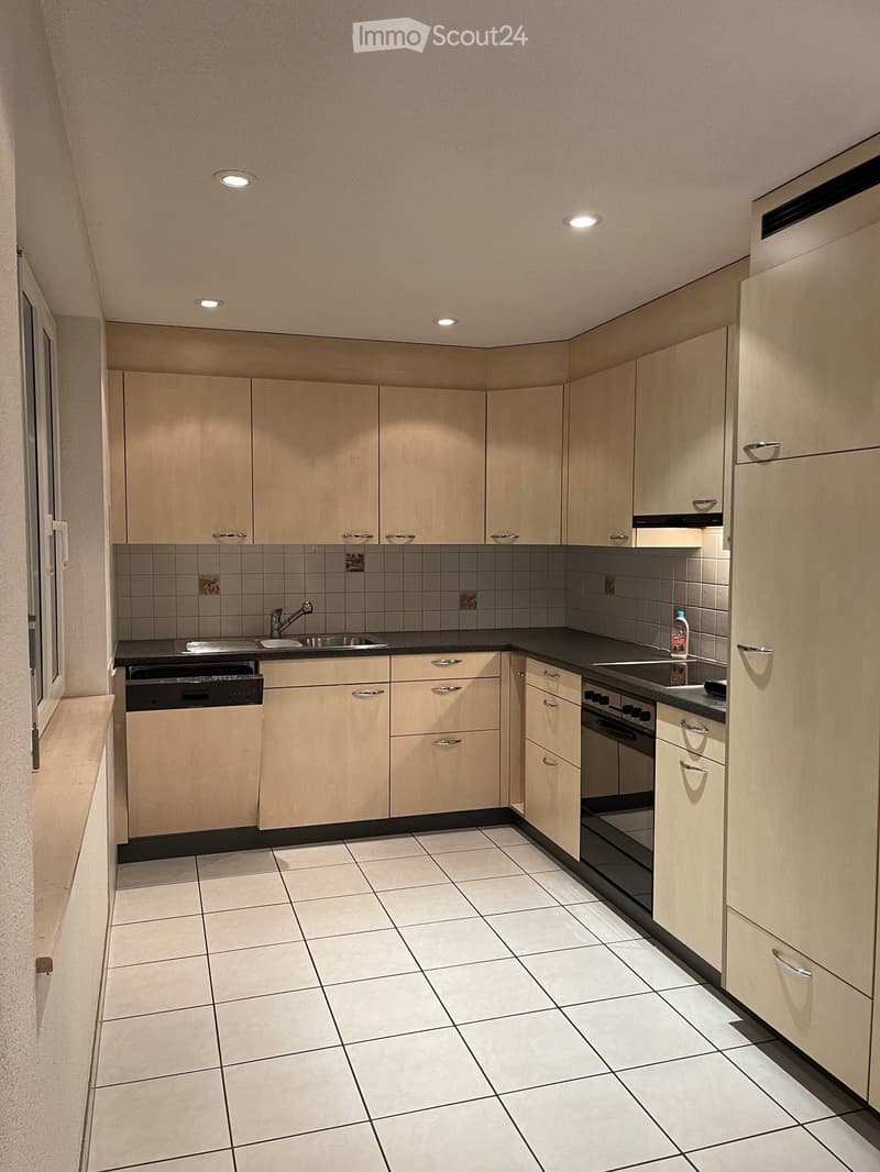 modern kitchen with white tiles, wooden cabinets, black countertops, stainless steel sink, dishwasher, washing machine, gas stove, refrigerator