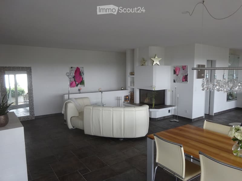 Modern living room with white leather sofa, dining table with chairs, fireplace, large mirror, and decorative items.