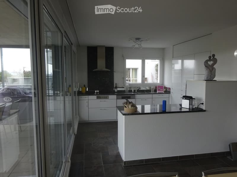 Modern kitchen with white cabinets, black countertops, stainless steel appliances, and a central island with a black countertop.