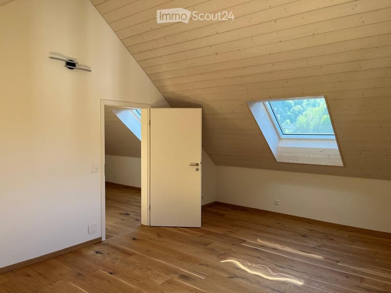 Empty attic room with wooden floors, white walls, and skylight windows. No furniture or equipment present.