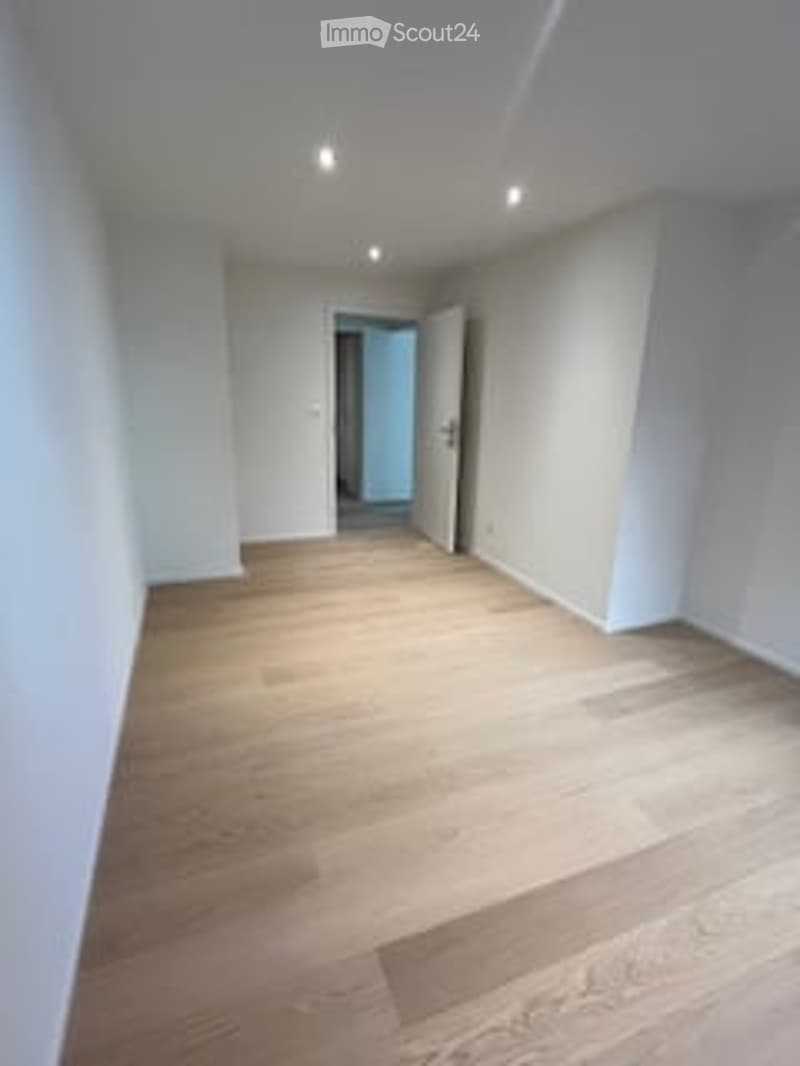Completely empty room with light wooden flooring and white walls. No furniture or equipment.