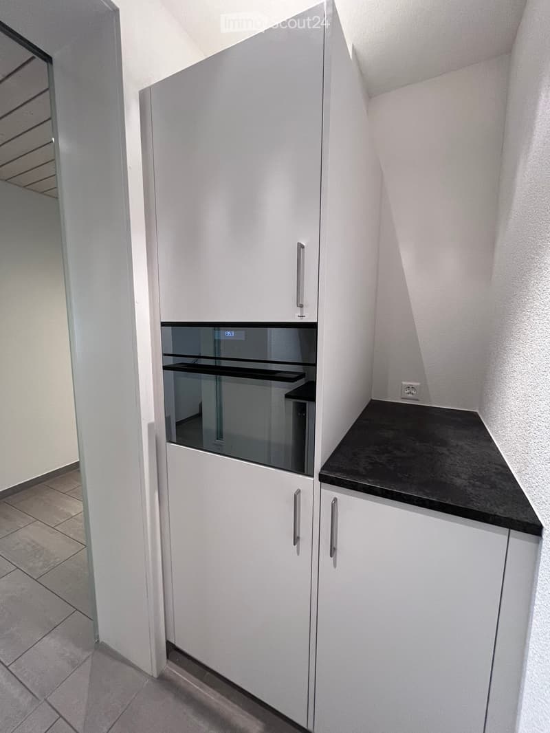 Modern kitchen with white cabinets, black countertop, and built-in oven.