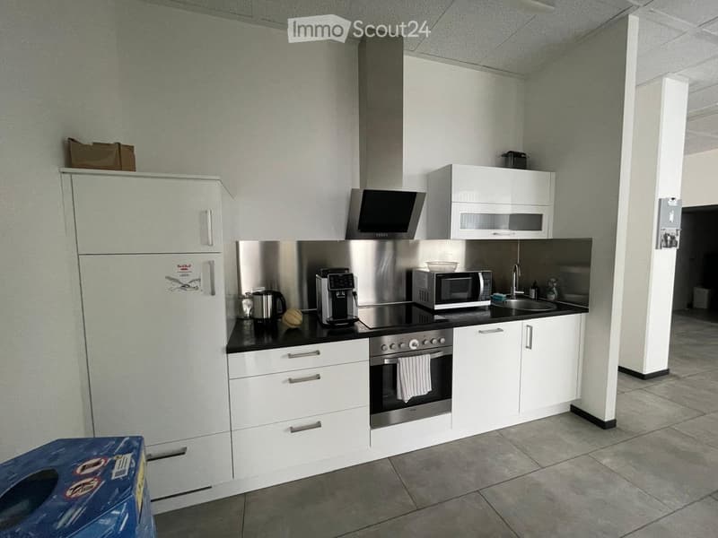 Modern kitchen with white cabinets, stainless steel appliances, and a black countertop.