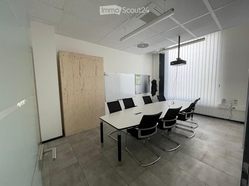Conference room with a large white table, black chairs, a projector screen, and a whiteboard.