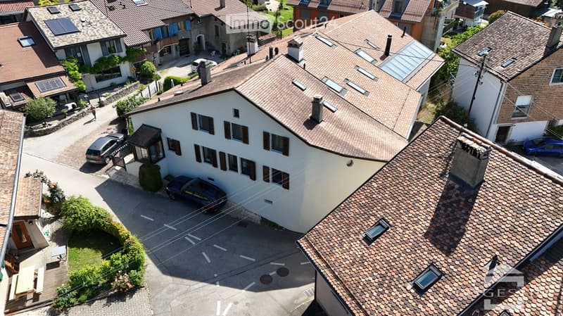 Aerial view of a residential area with multiple houses, tiled roofs, and parked cars in driveways.