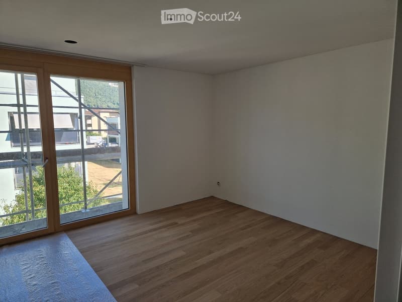 Empty room with wooden flooring, white walls, and large sliding glass doors leading to an outdoor area.