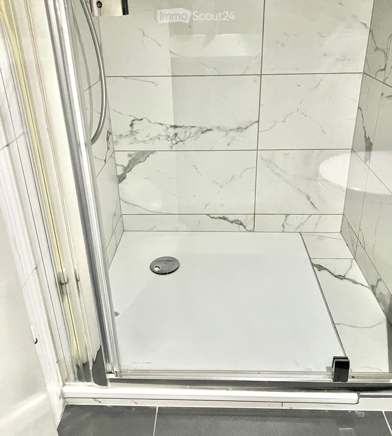 Modern shower with marble tiles, glass enclosure, and a sleek design.