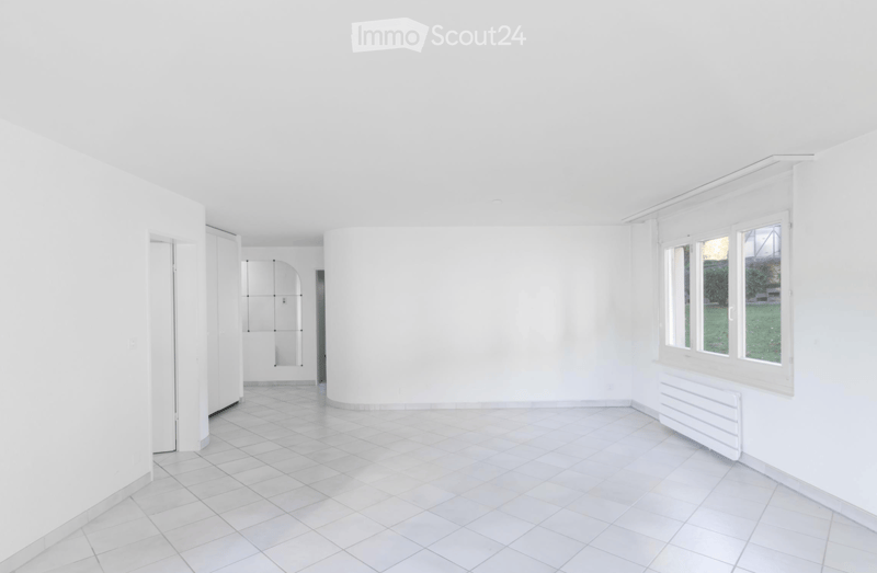 Empty room with white walls, tiled floor, large windows, and a radiator. No furniture or equipment present.