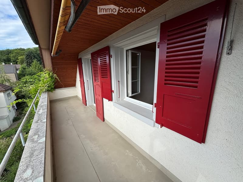 Balcony with wooden ceiling, red shutters, and a view of greenery.