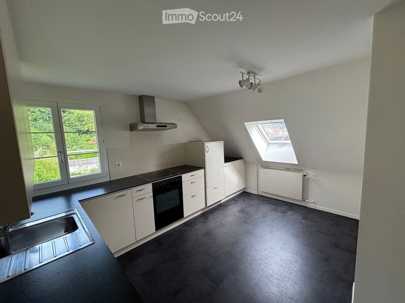 Modern kitchen with dark tiled floor, white cabinets, stainless steel sink, oven, and range hood. Features large windows and a skylight.