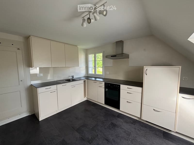 Modern kitchen with white cabinets, black countertops, and a stainless steel range hood. Features a sink with a faucet, an oven, and built-in lighting.